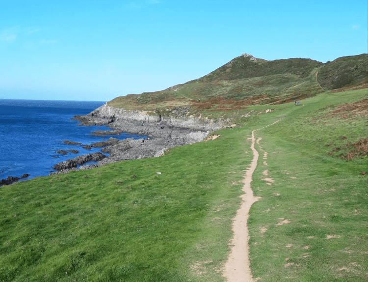 A pale sandy track beside the cliffs and sea on the UK coast